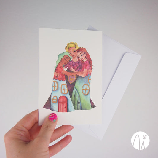 Friendship greeting card — original illustration of three women hugging, wearing house-shaped dresses that symbolize friendship as a warm and loving home, on a white background. It includes the envelope.