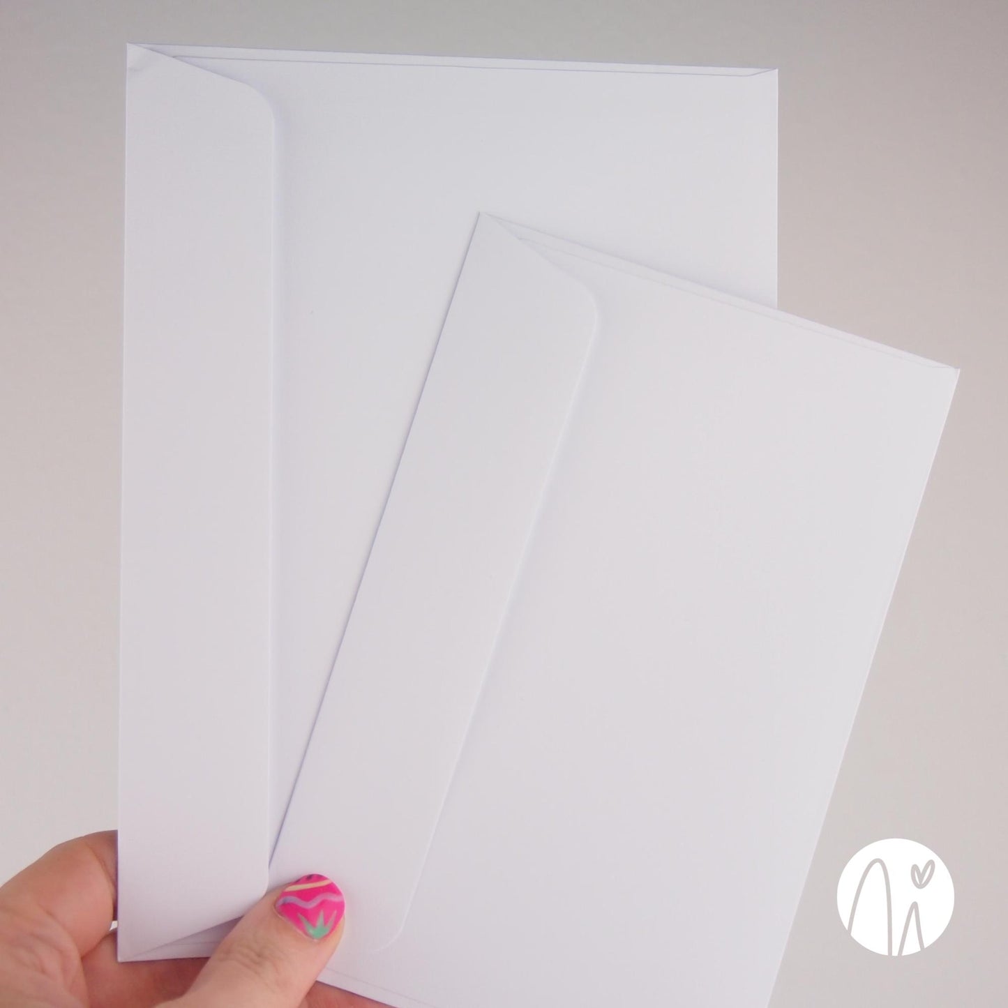 Hand holding a stack of white envelopes on a plain background